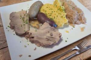 Teller mit Schlachtplatte bestehend aus Blut- und Leberwurst, Kesselfleisch und Sauerkraut